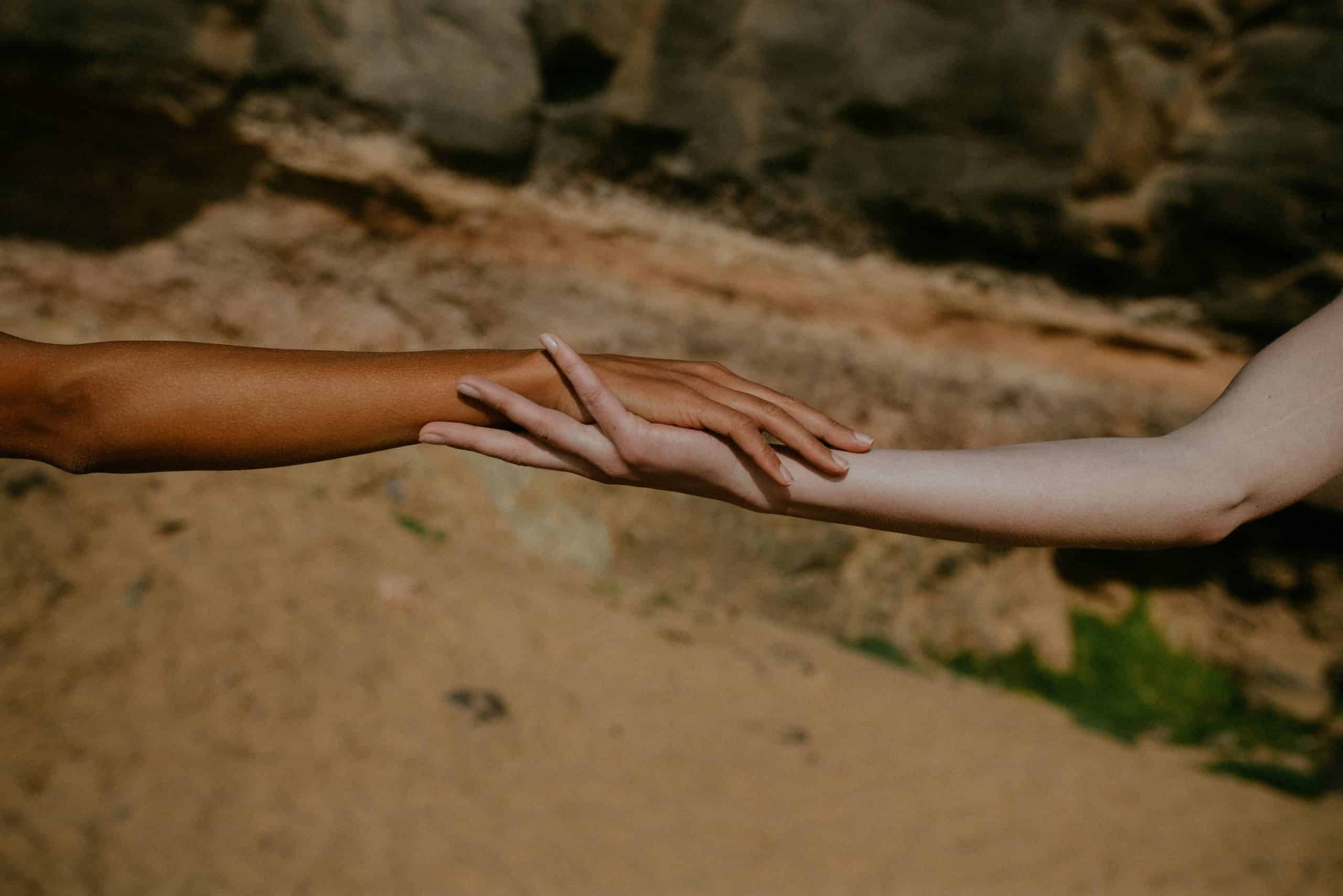 Two arms white and black holding each other